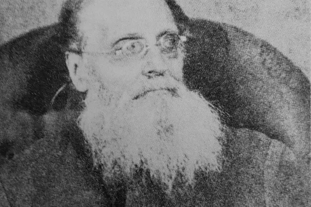 J. L. Runeberg istumassa valokuvassa, parta ja silmälasit, katse sivulle
