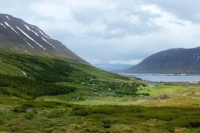 Vihreä laakso ja vuono vuorten välissä, rannalla pieni kylä.